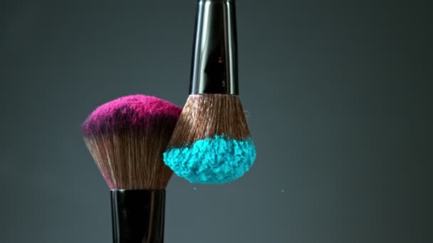 Szczotki do makijażu dotykają się na ciemnym tle i drobnych cząsteczkach kosmetyków, w zwolnionym tempie. — Wideo stockowe