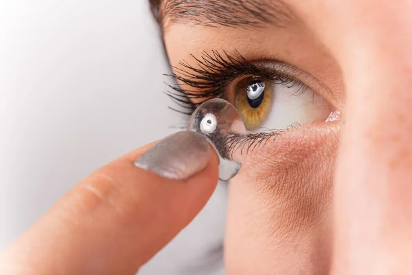 Mladá žena dává kontaktní čočky do oka. — Stock fotografie
