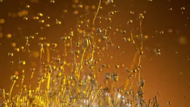 Super ralenti prise de vue de l'huile éclaboussante sur fond doré à 1000fps.