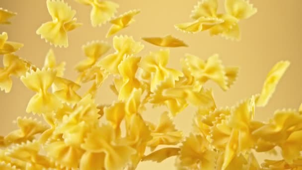 Super slow motion van vliegende ongekookte Italiaanse pasta op gouden achtergrond. — Stockvideo