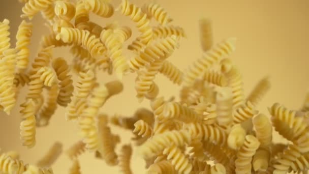 Super Zeitlupe des Fliegens ungekochte italienische Pasta auf goldenem Hintergrund. — Stockvideo