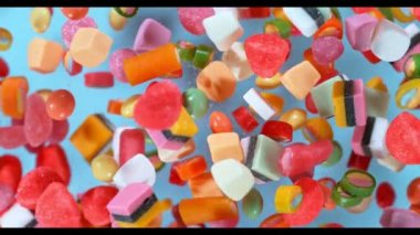 Pastel arka planda yavaş çekimde uçuşan tatlı şekerler. Yüksek hızlı sinema kamerasıyla çekilmiş.