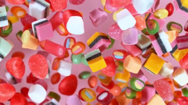 Sweet candies flying in slow motion against pastel background. Filmed on high speed cinema camera — Stock Video