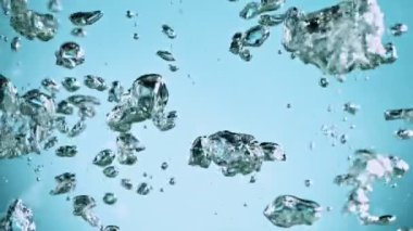 Sudaki çeşitli hava kabarcıklarının makro çekimi açık mavi arka planda yavaş çekimde yükseliyor