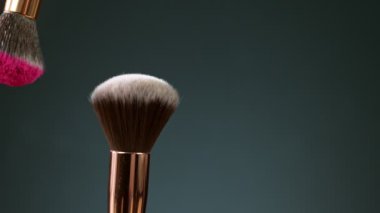 Makyaj fırçaları koyu arka plan ve küçük kozmetik parçacıkları, yavaş çekim birbirine dokunur.