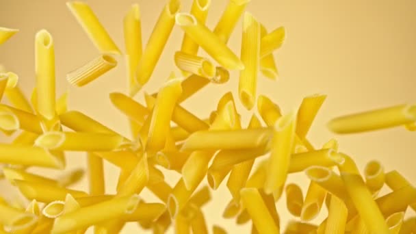 Super Zeitlupe des Fliegens ungekochte italienische Pasta auf goldenem Hintergrund. — Stockvideo