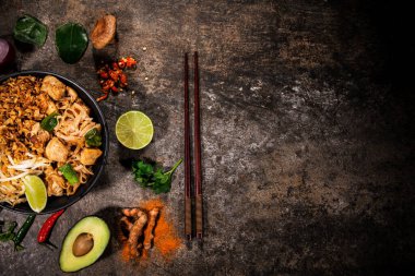 Köy taşından arka planda çeşitli malzemeler içeren Asya yemekleri, üst görünüm.