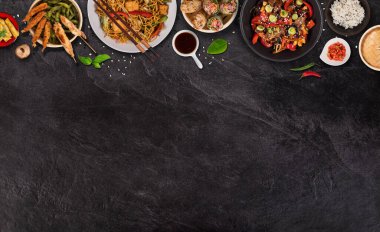 Köy taşından arka planda çeşitli malzemeler içeren Asya yemekleri, üst görünüm.