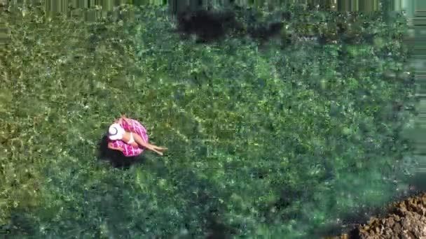 Jonge ontspannen vrouw in een badpak in het water op een opblaasbare donut ring. — Stockvideo