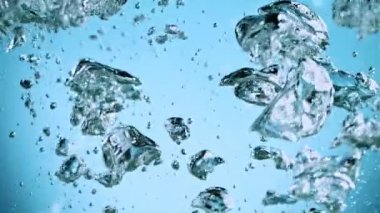 Sudaki çeşitli hava kabarcıklarının makro çekimi açık mavi arka planda yavaş çekimde yükseliyor