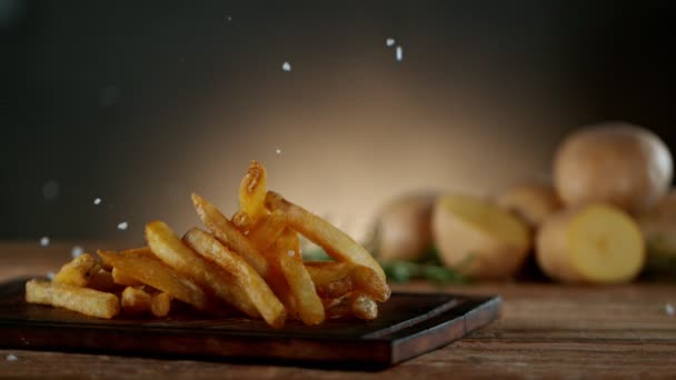 Tiro super lento do movimento de cair fritas francesas frescas na tabela de madeira — Vídeo de Stock