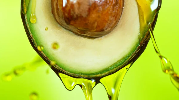 Fresh cut avocado with oil stream. — Stock Photo, Image