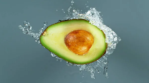 Movimento di congelamento dell'avocado affettato con spruzzi d'acqua — Foto Stock