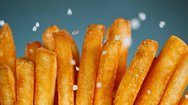 Congelar detalhe do movimento Tiro de adicionar sal em batatas fritas — Fotografia de Stock