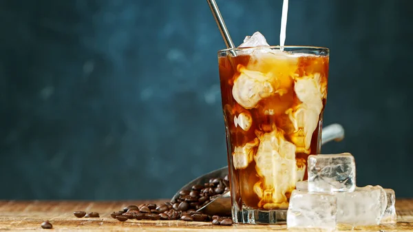 Pouring milk in iced coffee on grey background — Stock Photo, Image