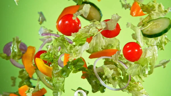 Flying vegetable salad isolated on green background. — Stock Photo, Image