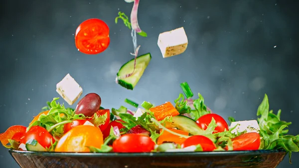 Salade de légumes volants sur fond gris. — Photo
