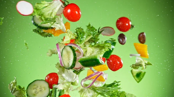 Latająca sałatka warzywna izolowana na zielonym tle. — Zdjęcie stockowe
