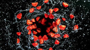 Siyah arka planda uçuşan taze olgun çilekler..