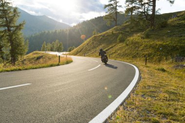 Alplerde motosiklet sürücüsü, açık gökyüzü ile güzel doğa.
