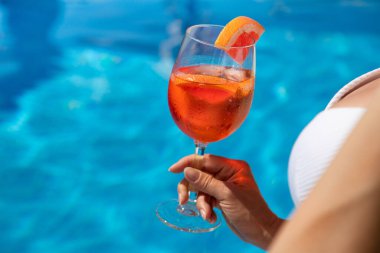 Yüzme havuzunun kenarında oturan şapkalı güzel kadın.