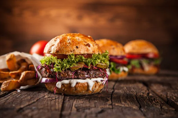 Sabrosas hamburguesas sobre mesa de madera. — Foto de Stock