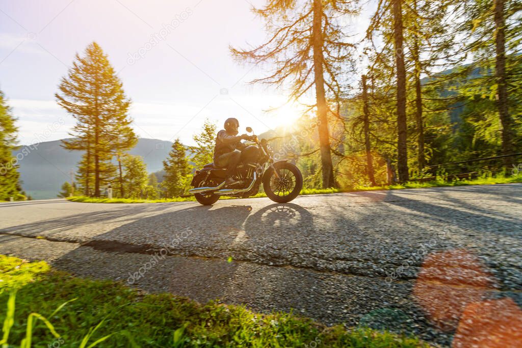 Motorcycle rider driving in Alps, beautiful nature with clear sky.