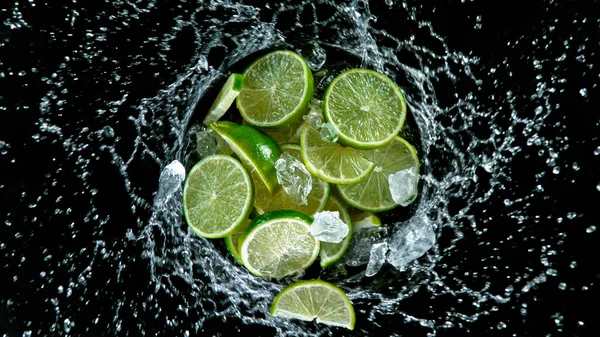 Limes freschi maturi che volano su uno sfondo nero. — Foto Stock