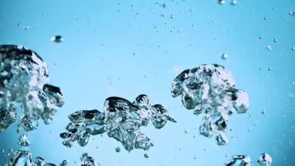 Macro shot van verschillende luchtbellen in water stijgt in slow motion op lichtblauwe achtergrond — Stockvideo