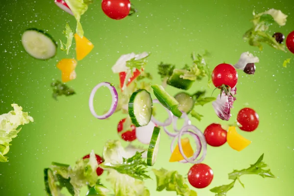 Fliegender Gemüsesalat isoliert auf grünem Hintergrund. — Stockfoto