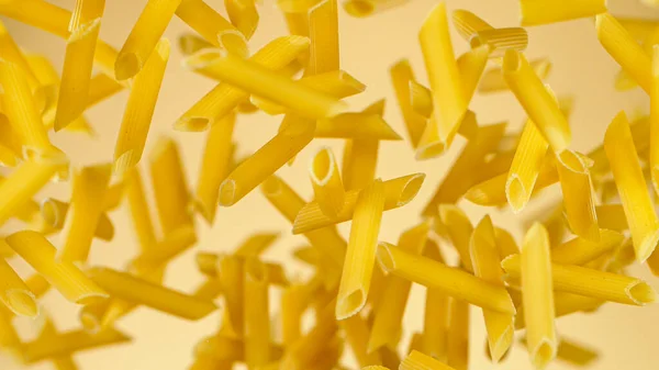 Frys rörelse av flygande okokt italiensk pasta på gyllene bakgrund. — Stockfoto