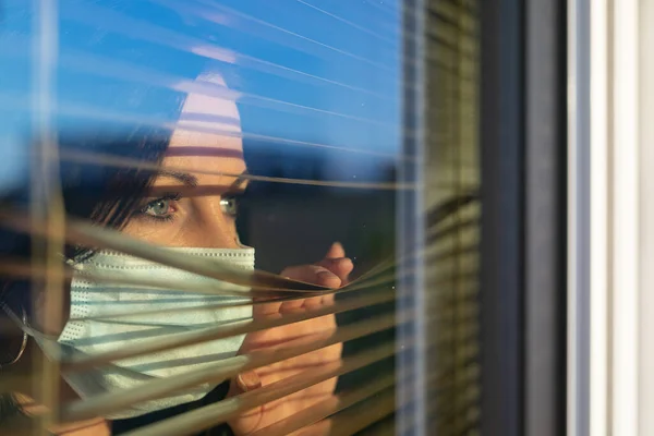 Frau mit Schleier schaut aus dem Fenster ihres Hauses, Konzept der Quarantäne während der Virenpandemie. — Stockfoto