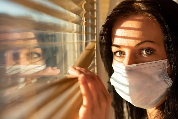 Frau mit Schleier schaut aus dem Fenster ihres Hauses, Konzept der Quarantäne während der Virenpandemie. — Stockfoto