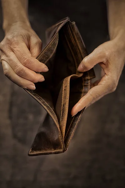 Empty wallet in the hands of an elderly man. Poverty in times of economic crisis