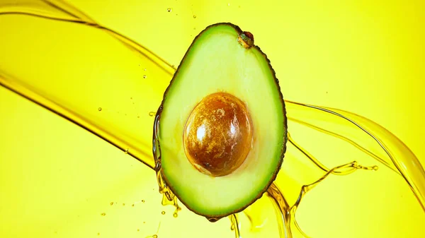Fresh cut avocado with oil stream. — Stock Photo, Image