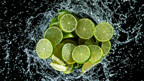 Limes freschi maturi che volano su uno sfondo nero. — Foto Stock