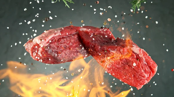 Detailní záběr létání chutné syrové hovězí steak na černém kameni pozadí — Stock fotografie