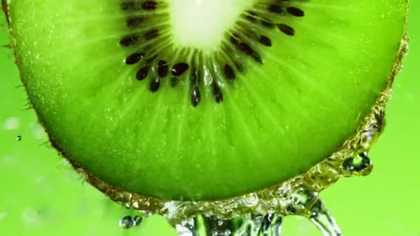 Super-Zeitlupe des Wasserspritzens auf frisch beleuchtete Kiwi-Scheibe. — Stockvideo