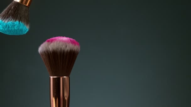 Makeup brushes touch each other on dark background
