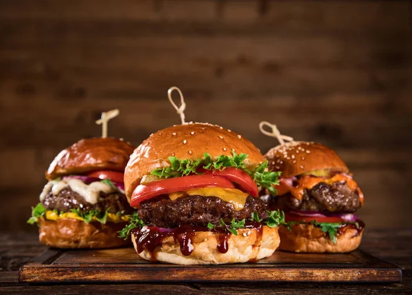 Smaczne hamburgery na drewnianym stole. — Zdjęcie stockowe