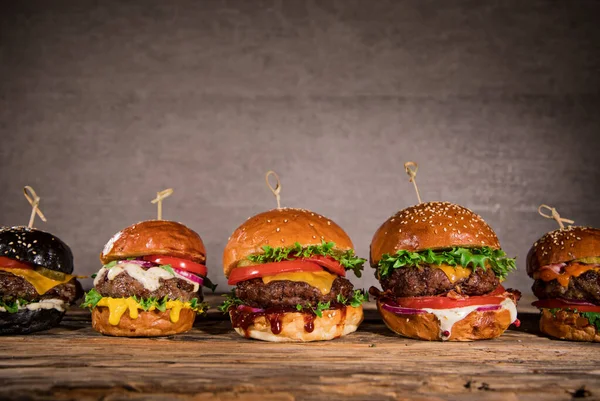 Sabrosas hamburguesas sobre mesa de madera. — Foto de Stock