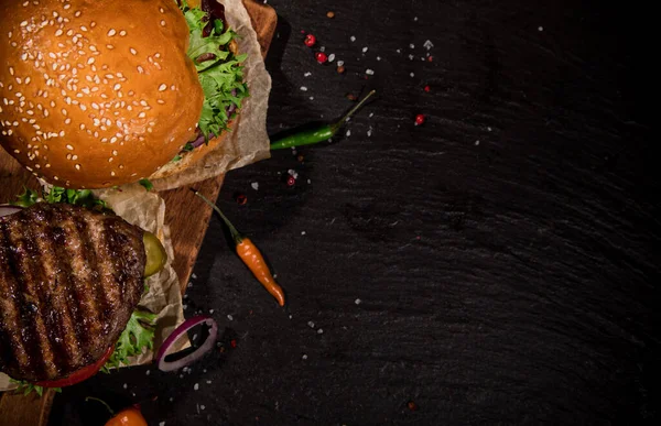 Sabrosas hamburguesas en mesa de piedra negra. — Foto de Stock