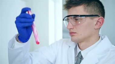Beyaz ceket Holding test tüp kırmızı numune Ile laboratuar Işçisi. Yavaş hareket efekti.