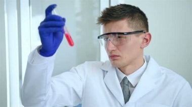 Beyaz ceket Holding test tüp kırmızı numune Ile laboratuar Işçisi. Yavaş hareket efekti.