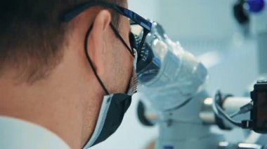 Diş hekimi modern ofiste Dental mikroskop kullanıyor. Tıbbi teknoloji konsepti