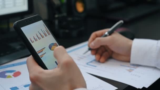 スクリーン携帯電話の株式市場データをチェックする投資家 スローモーション効果 — ストック動画