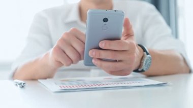 Cep telefonu kullanan bir iş adamı. Masadaki borsa analizleriyle ilgili iş raporu. İş ve Mali Başarı Konsepti. Kapat..