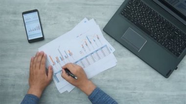 İşadamı, kağıt ve dizüstü bilgisayardan kar raporlarını kontrol ediyor. Belgeler ve finansal başarı kavramı.