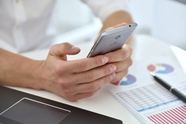 Cep telefonlu bir işadamı, grafiği analiz ediyor ve iş planlarını kontrol ediyor. Yatırım ve finansal konsept.