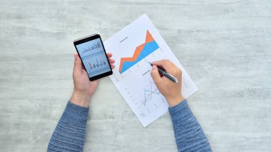 Tüccar, kağıt ve cep telefonundan kâr bildirmiş. Belgeler ve finansal başarı kavramı.